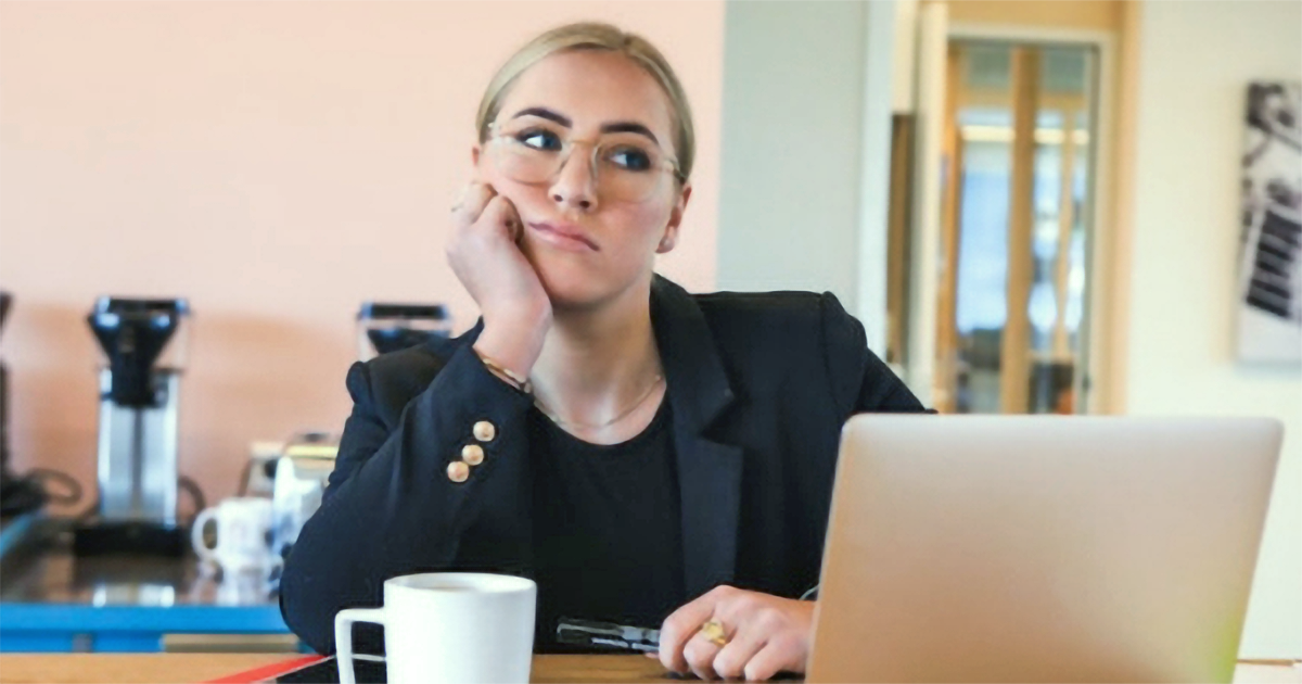Bored woman sitting at her desk in front of her laptop